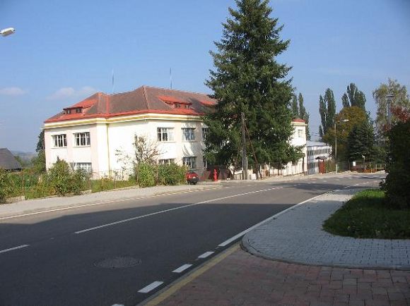    Budovu sou�asn� �koly pon�kud zasti�uje mohutn� jehli�nan, zasazen� p�ed desetilet�mi p�i pr�ci na pozemku. Pod �kolou vyrostla hradba vysok�ch topol�. 